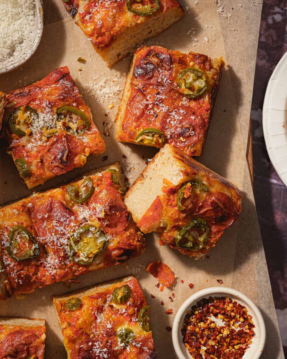Slices of focaccia pizza on a parchment-lined cutting board. 