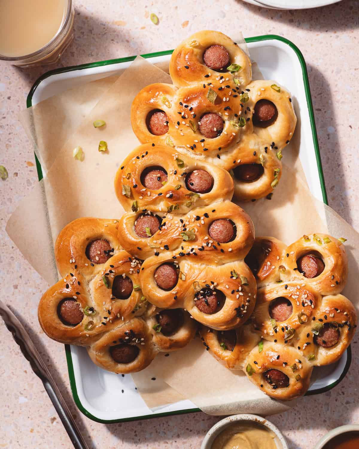 Hot dog flower buns stacked on an enamel tray. 