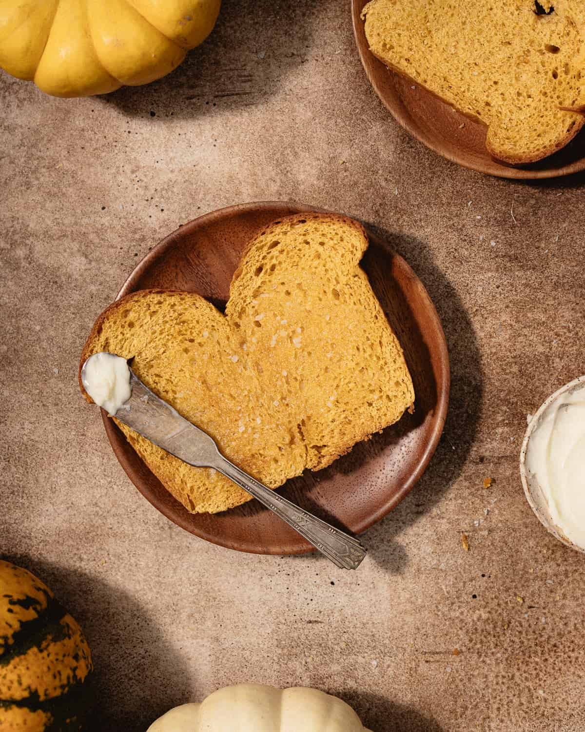 Slice of brioche toast slathered with butter on a small dessert plate.